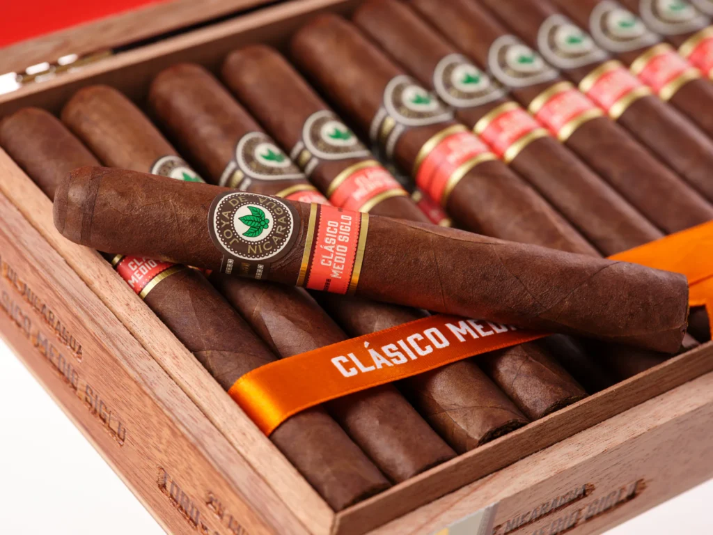 Open wooden box of Joya de Nicaragua cigars with an orange “CLÁSICO MEDIO SIGLO” ribbon.