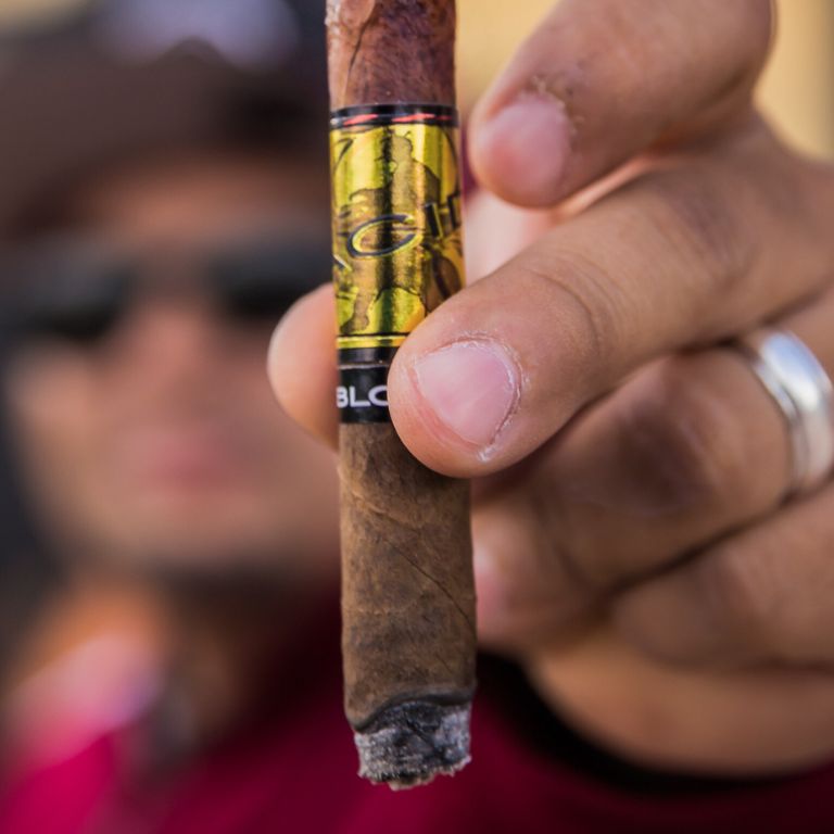 a hand holding an acid blue cigar