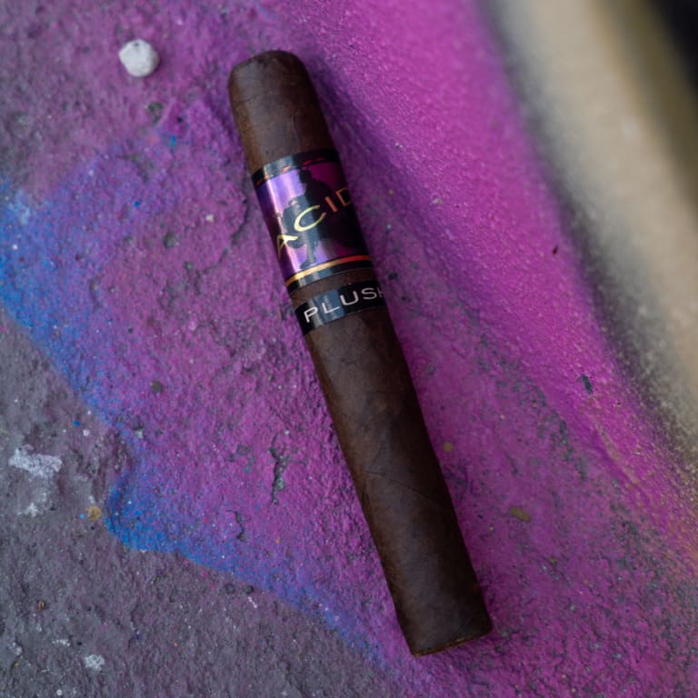 A cigar rests elegantly on a vibrant purple wall