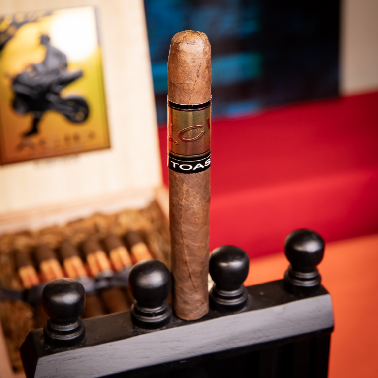 A Drew Estate Subculture Toast Cigar standing with a box of cigars on the back