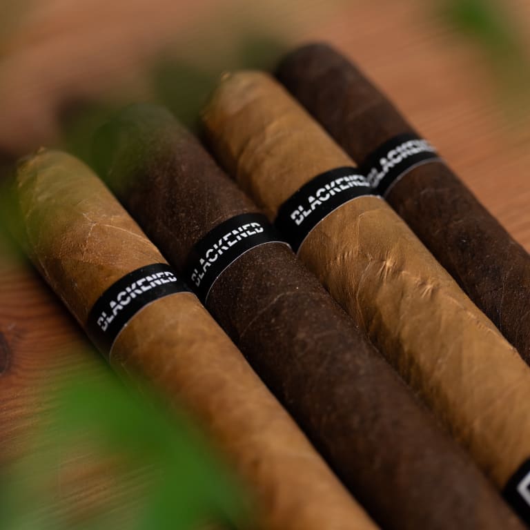 4 blackened cigars on a wooden surface