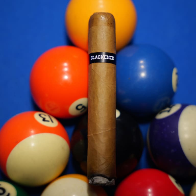 blackened cigar on colorful pool table balls
