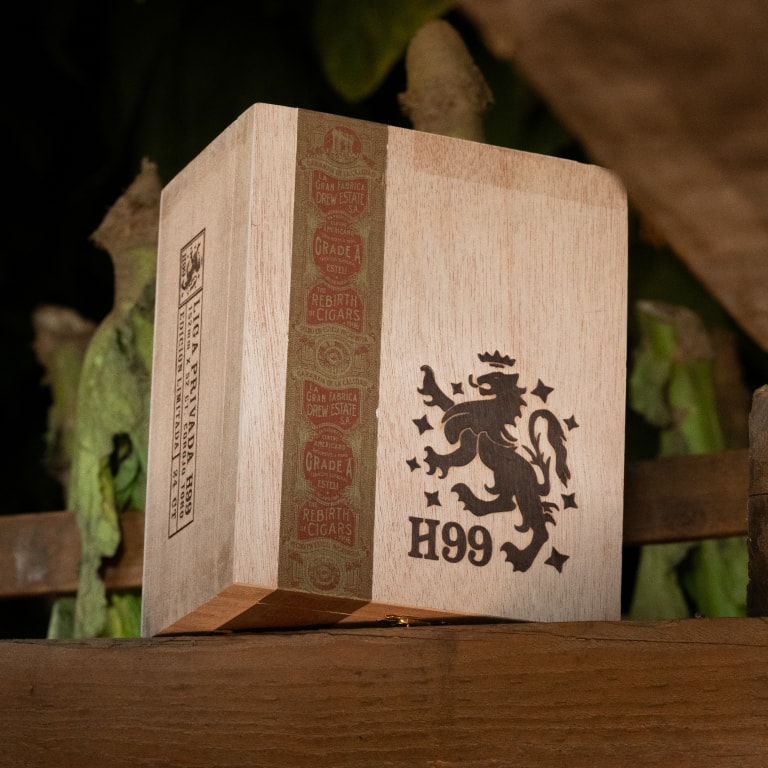 Elegant wooden cigar box engraved with a lion Liga Privada H99 emblem, featuring Drew Estate and Grade A stamps, displayed on a rustic surface at the Connecticut Barn Smoker Event.
