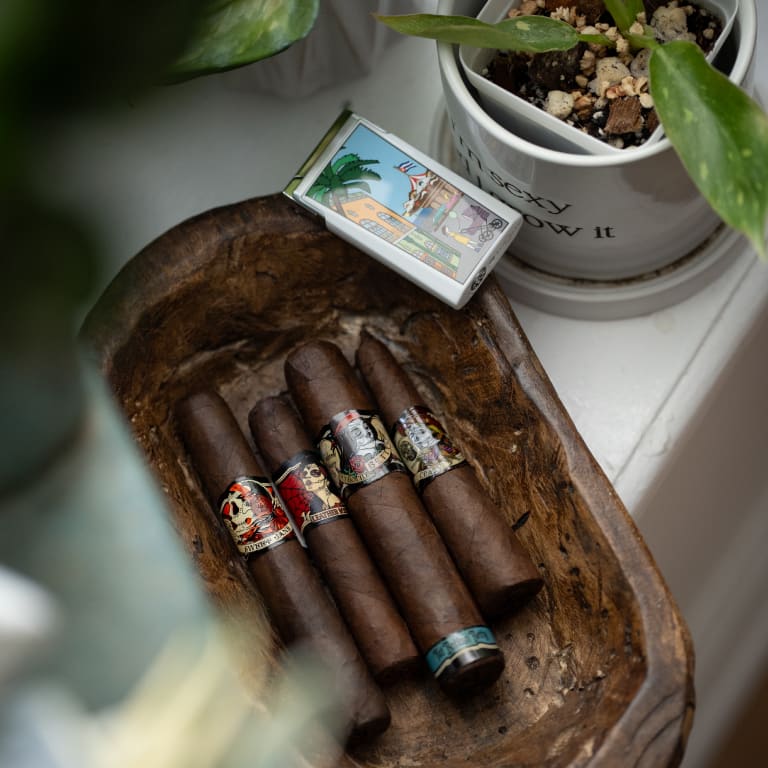 deadwood fatbottom betty and leather rose cigars in a wooden bowl next to a plant