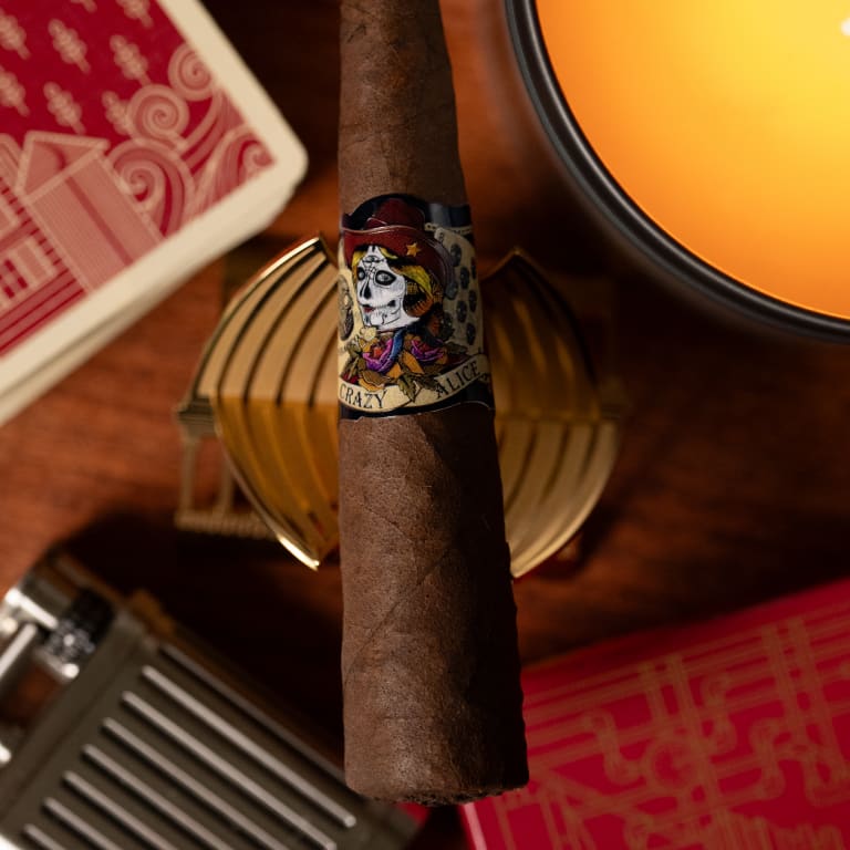 deadwood crazy alice cigar resting on a table surrounded by playing cards and a flask