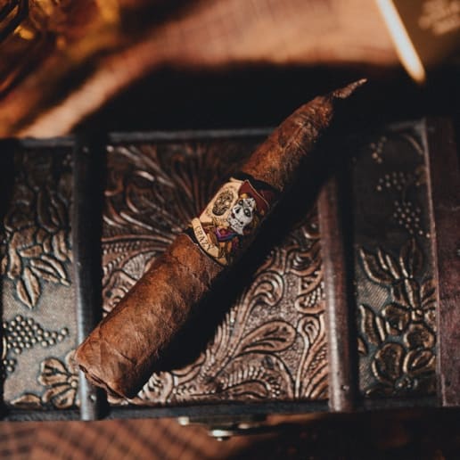 A Deadwood Crazy Alice cigar rests elegantly atop an aged wooden box