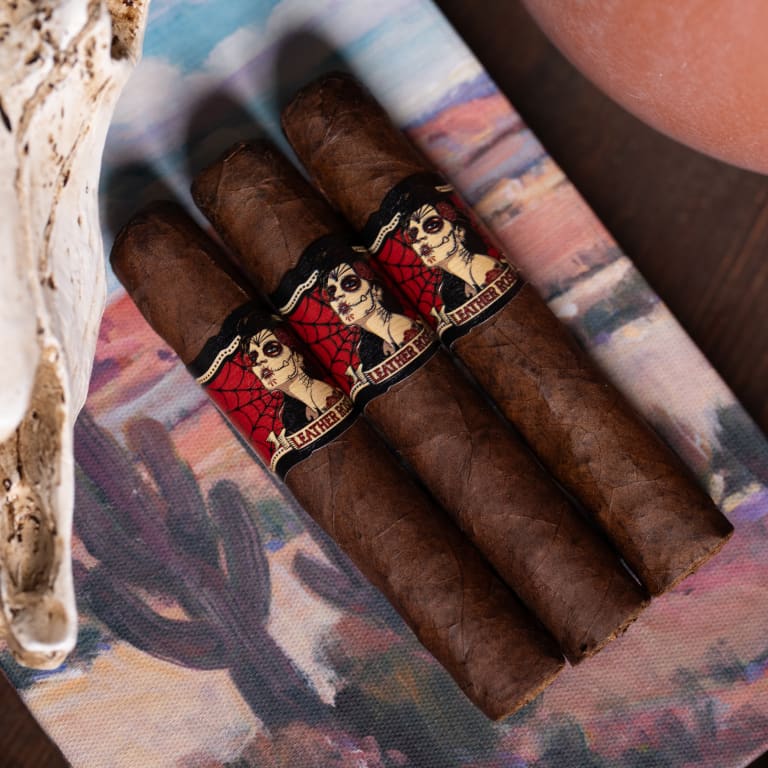 3 deadwood leather rose cigars, rest on a wooden table