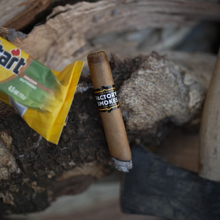 Factory Smokes lighted cigar on some wooden rolls