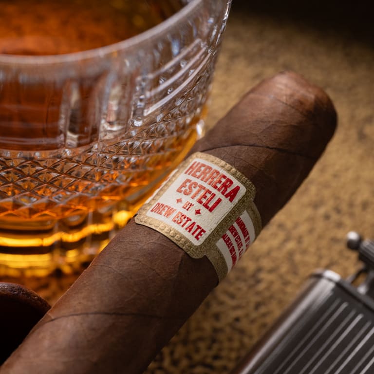 herrera esteli habano cigar next to a glass of whiskey