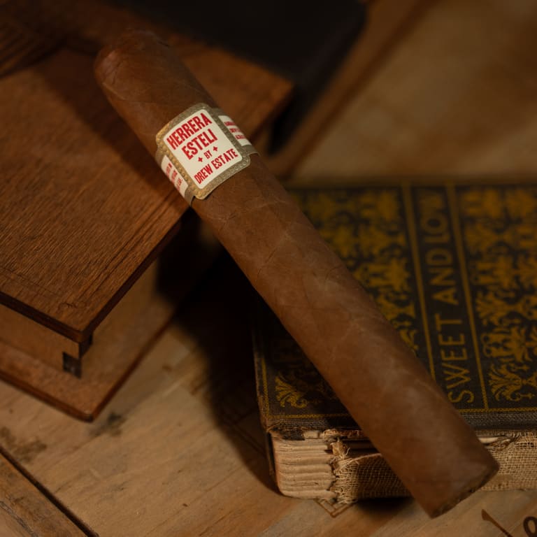 herrera esteli habano cigar laying on top of a book on a wooden surface