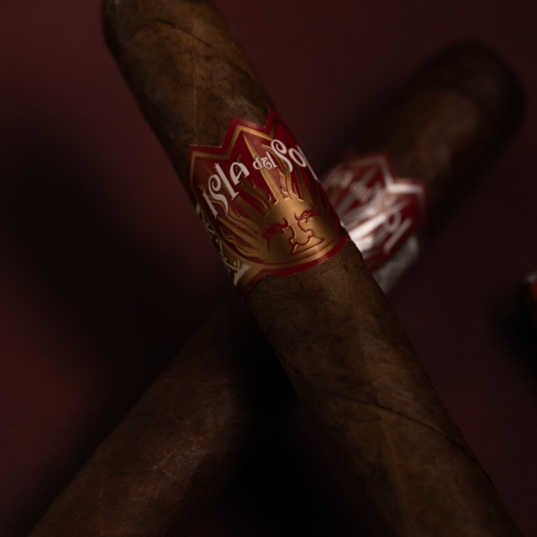 Two Isla del Sol CIgars over a dark red backgrund