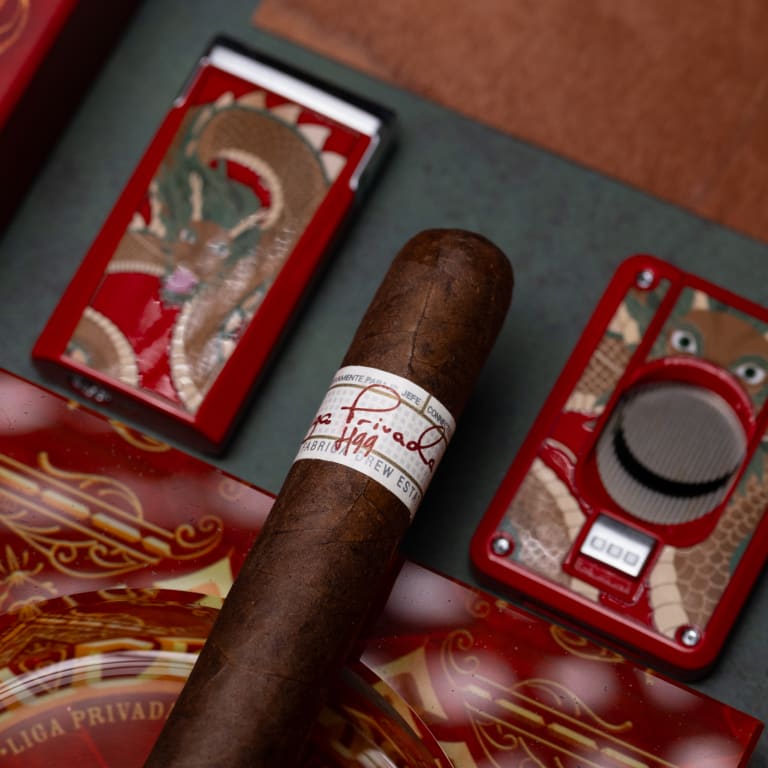 A Liga Privada H99 cigar and a lighter elegantly placed on a wooden table