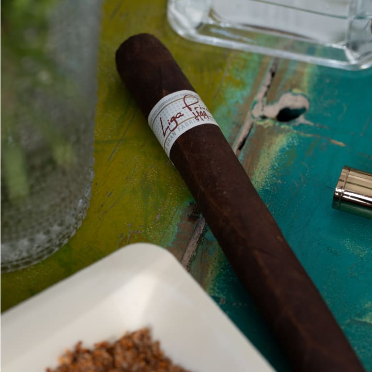 liga privada t52 cigar resting on a green-blue surface