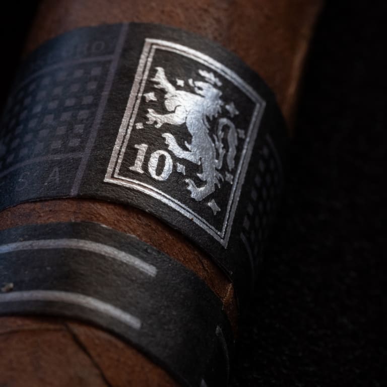A close-up of a Liga Privada 10 cigar band featuring a silver lion emblem
