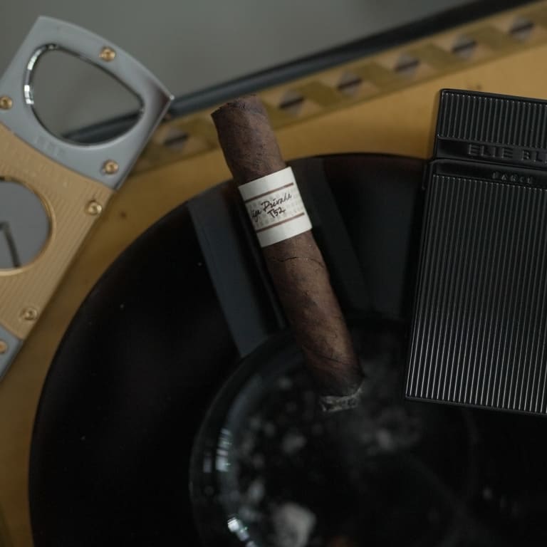 liga privada t52 cigar sits on top of a record alongside a bottle opener