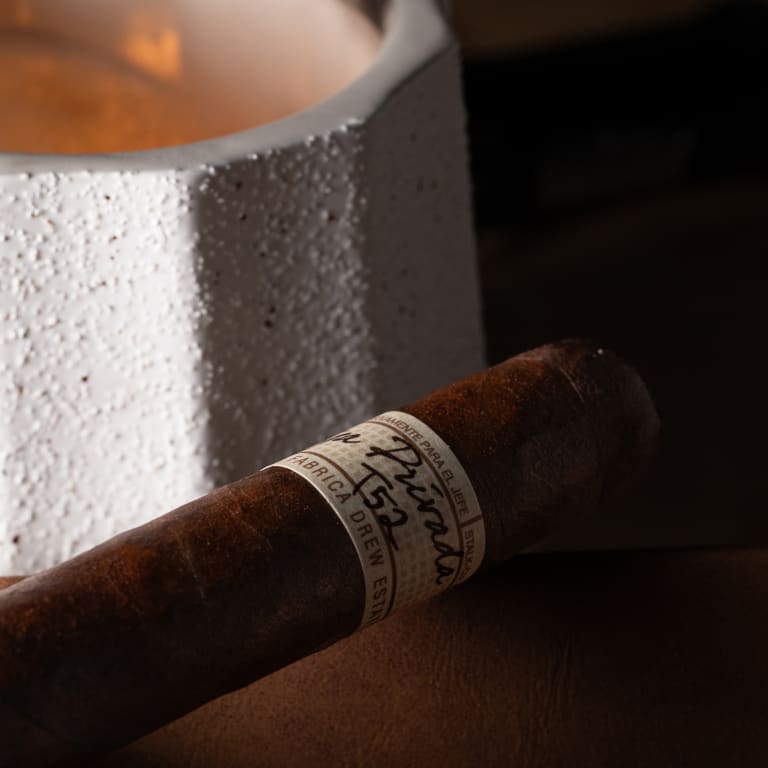 Liga Privada T52 cigar resting next to a lit candle