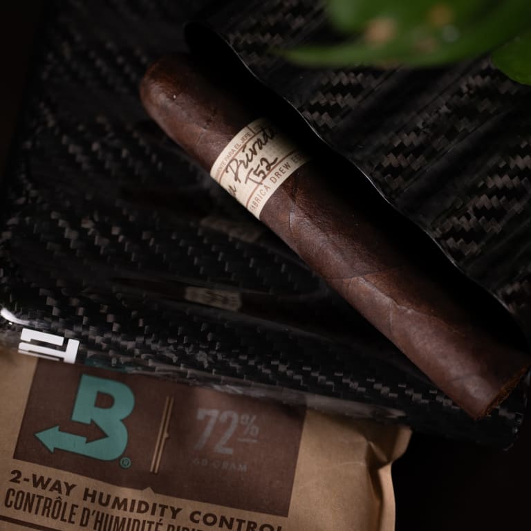 A Liga Privada T52 cigar rests elegantly on a sleek black bag
