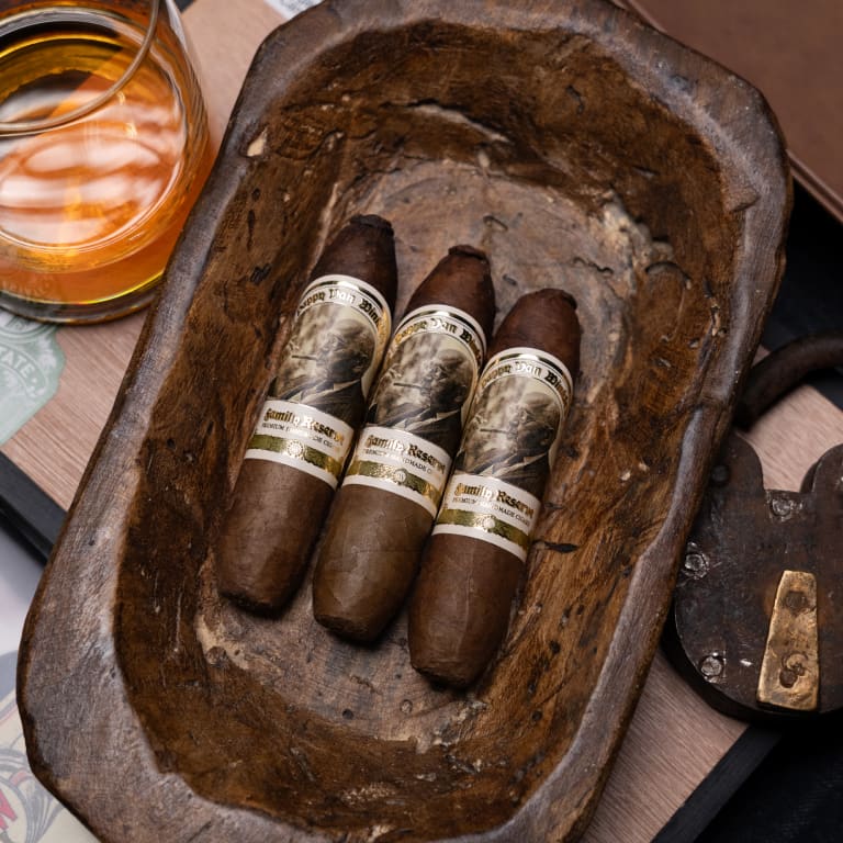 Three cigars resting in a wooden bowl on a table