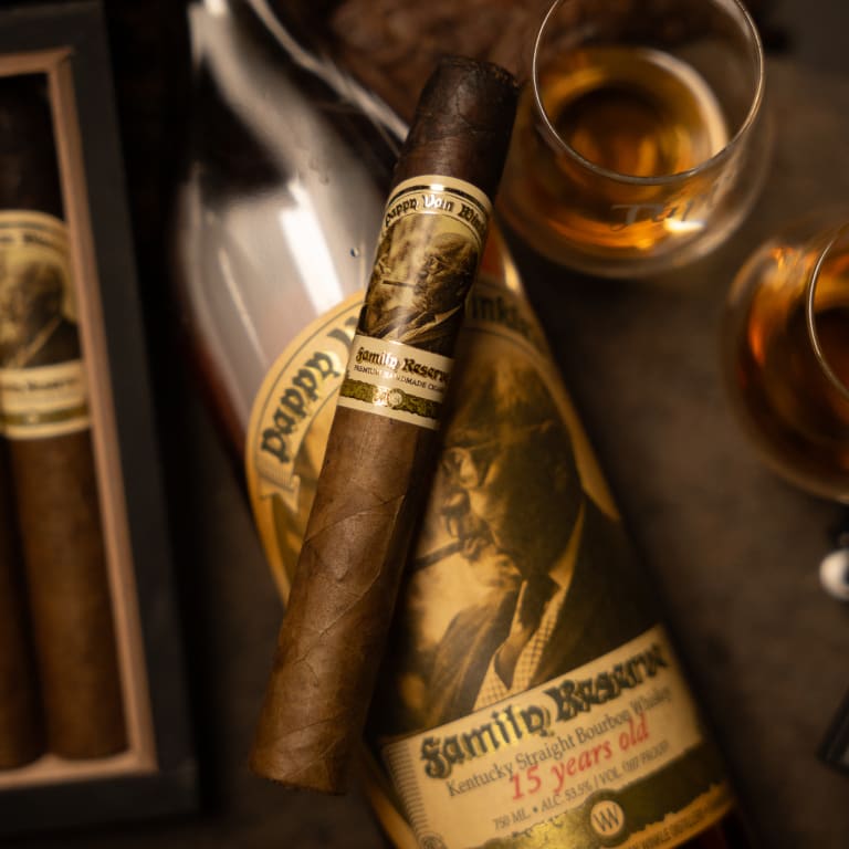 pappy van winkle cigar laying on top of a bottle of bourbon whiskey