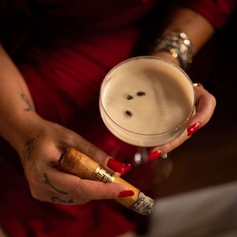 someone holding a tabak especial cigar by an espresso martini
