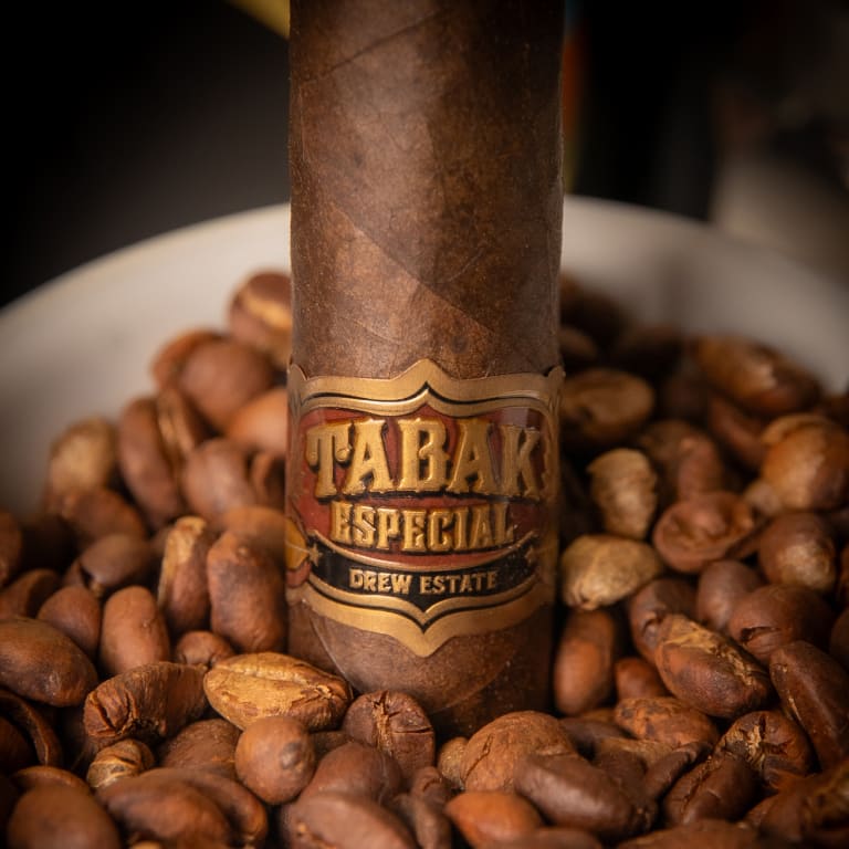 tabak especial cigar in a mug of coffee beans
