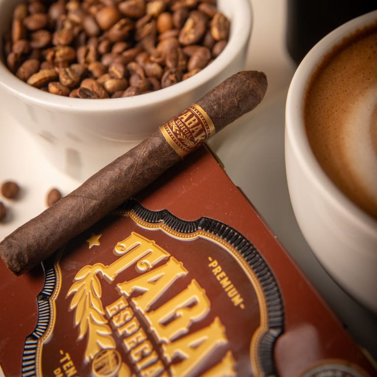 tabak especial negra cigar resting on a book by two coffee mugs