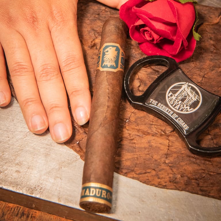 undercrown maduro cigar with the hand of a man and a cigar cutter