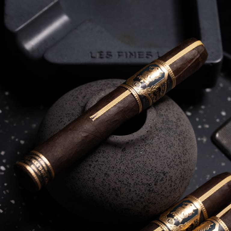 A close-up of an Undercrown UC10 cigar resting on a smooth black stone surface