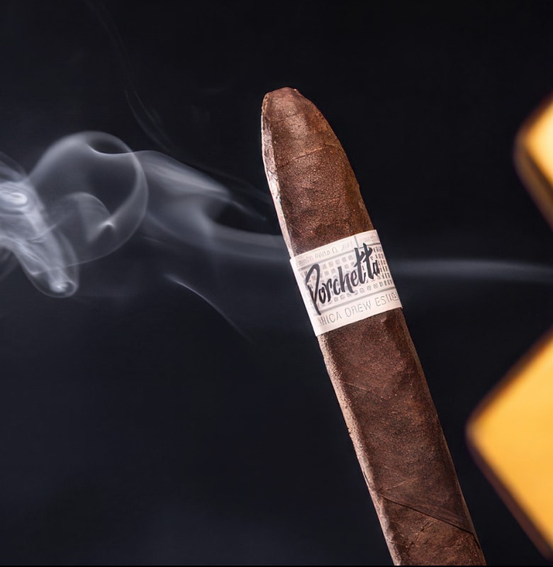 A close-up view of a neatly arranged pile of cigars resting on a dark, textured background