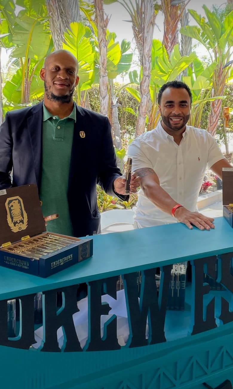 two young men at a Drew Estate booth displaying boxes of undercrown cigars