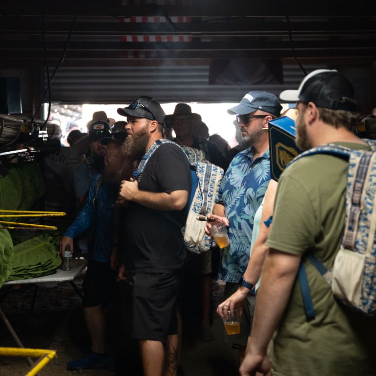 A group of people gathered around a table with beer, enjoying drinks while observing tobacco leaf production