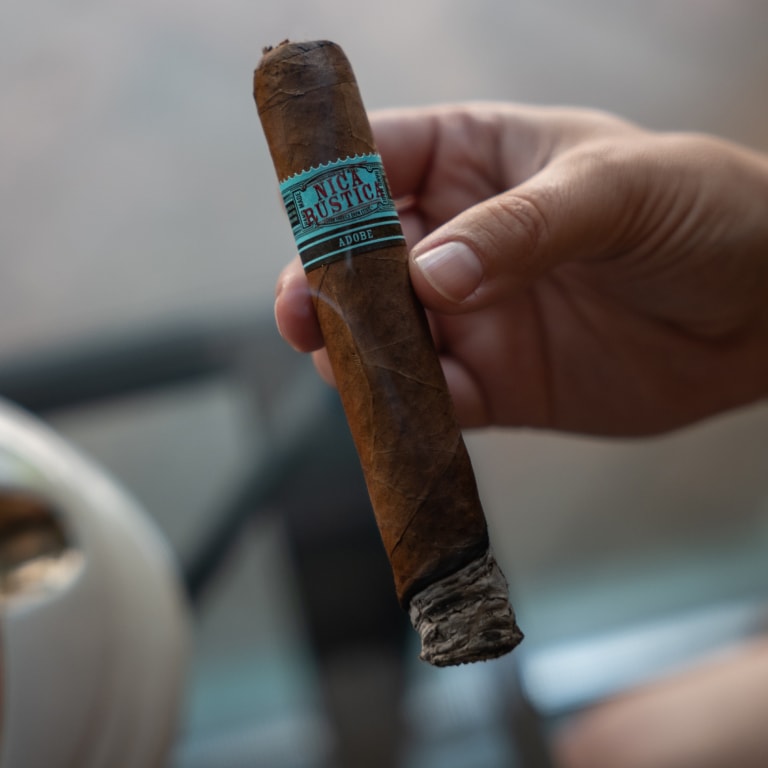 a man's hand with a Nica Rustica Adobe cigar