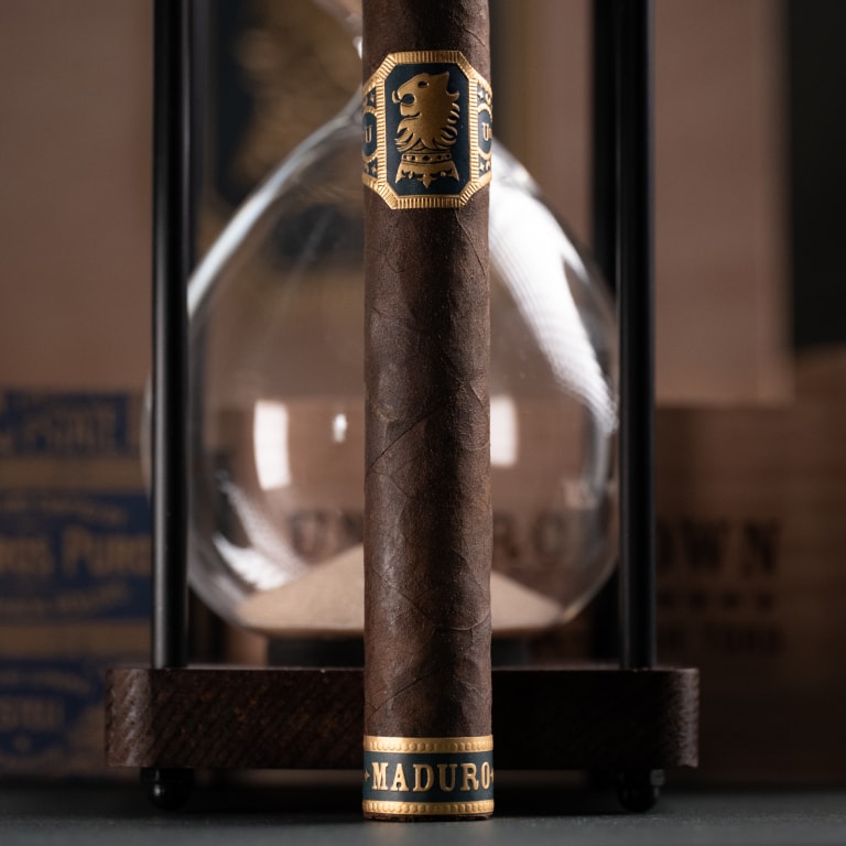 Undercrown maduro cigar in front of an hourglass