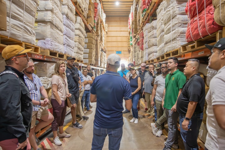 a large group of people listen attentively to an explanation on the guided tour of the cigar factory
