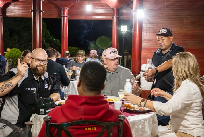 a person offers cigars to a group of people at a dinner