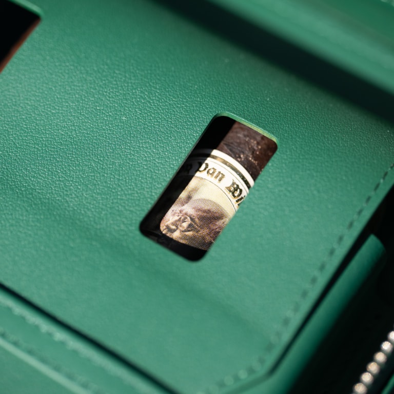Close-up of a green leather case with a rectangular cutout revealing part of a Pappy Van Winkle cigar, captured as a creative detail during the Kentucky Castle Family Reunion