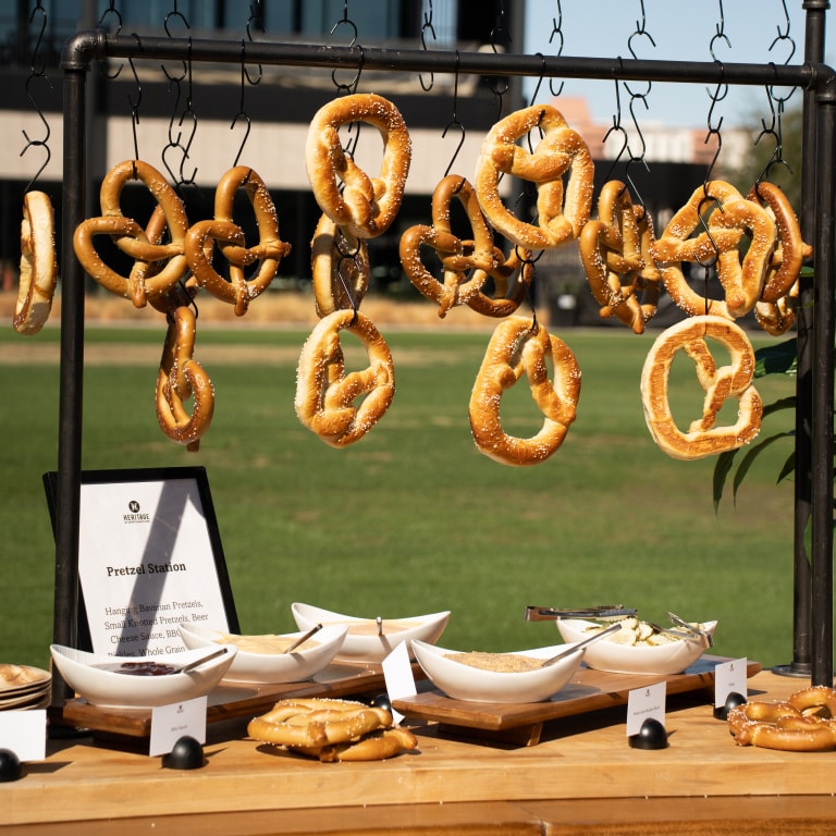 Pretzel station at the Tour de Liga Experience featuring Bavarian pretzels hanging on hooks, accompanied by an array of dips —offering a gourmet snack experience in a stylish event setting.