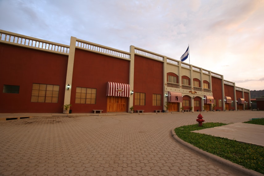 A large, modern building with a flagpole in front, showcasing a clear blue sky in the background.