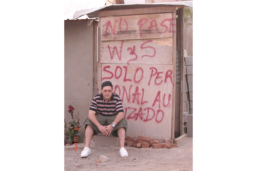 Jonathan Drew relaxes on a bench, with a colorful graffiti mural on the building behind him