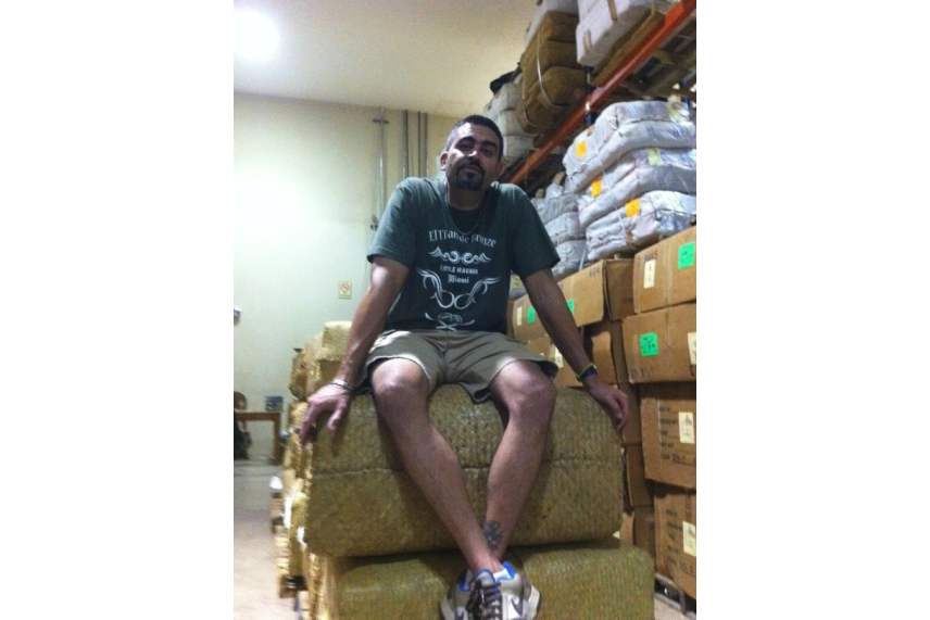 a man sitting top a large stack of packages in a storage room
