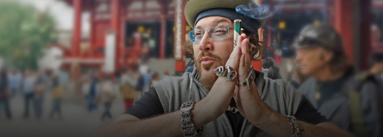 Jonathan Drew in front of a in front of a traditional red temple structure, with other visitors in the background